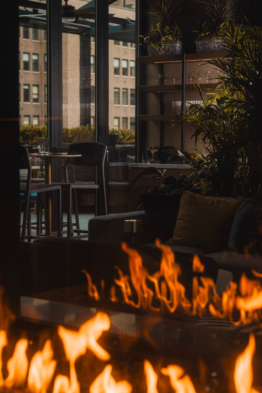 Rooftop lounge framed through a fire feature, the city beyond