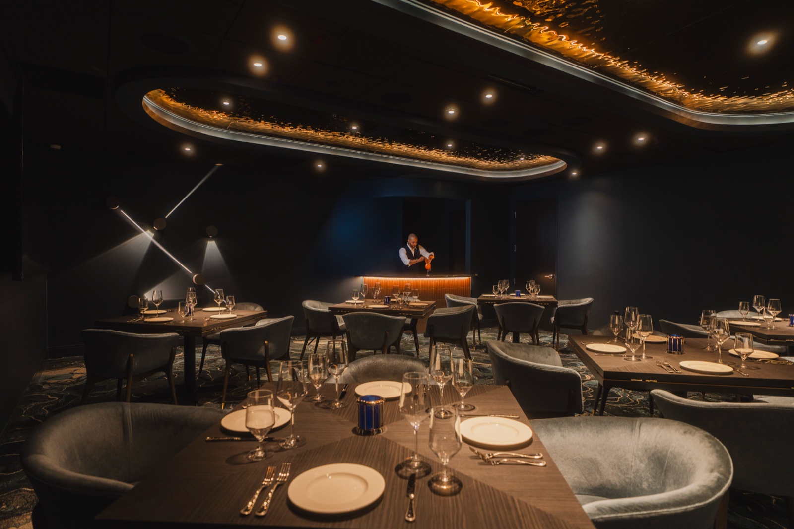 Wide dining room with a lit bar and set tables