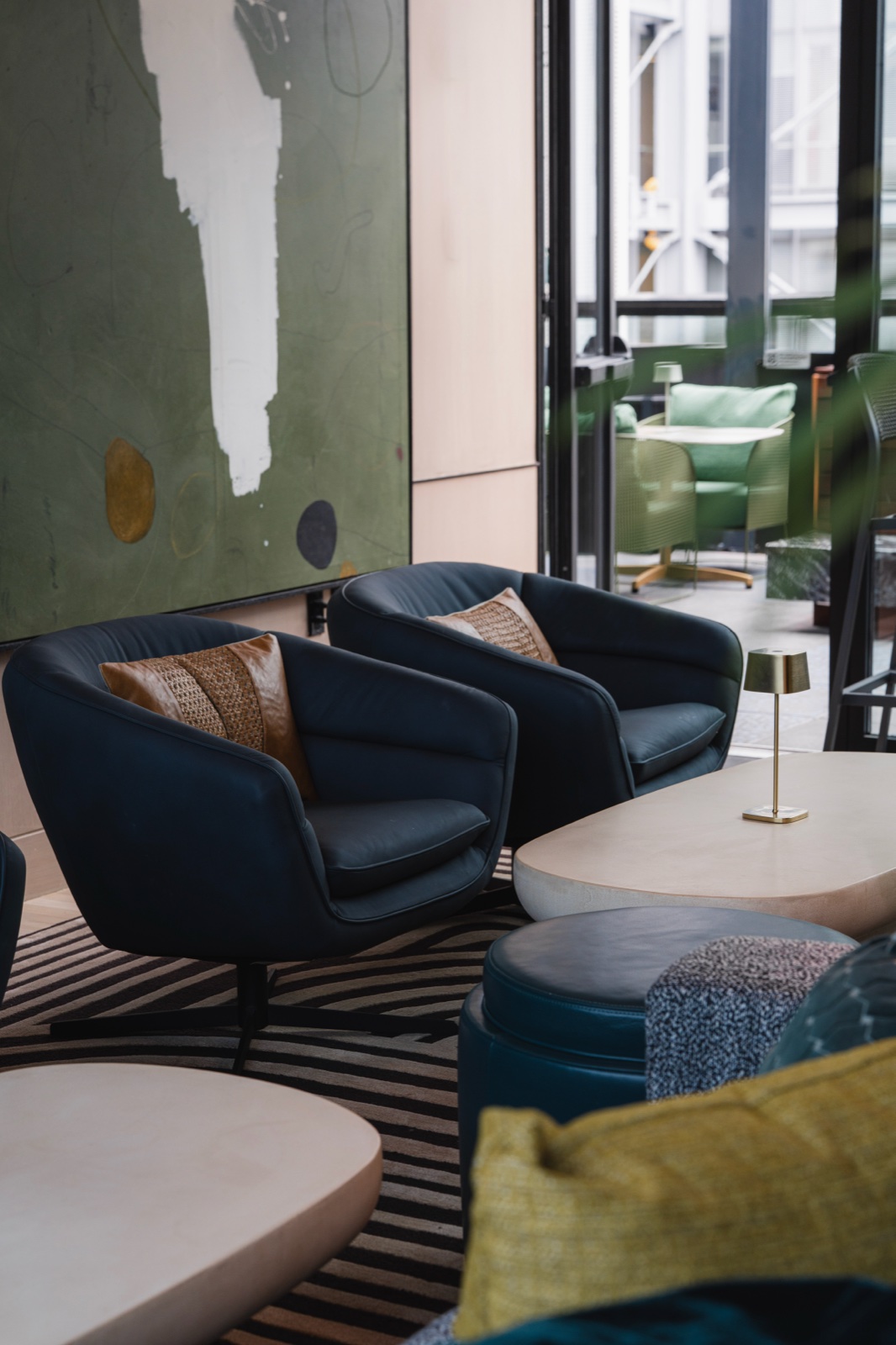 Daylight lounge — navy chairs, a brass lamp, a striped rug