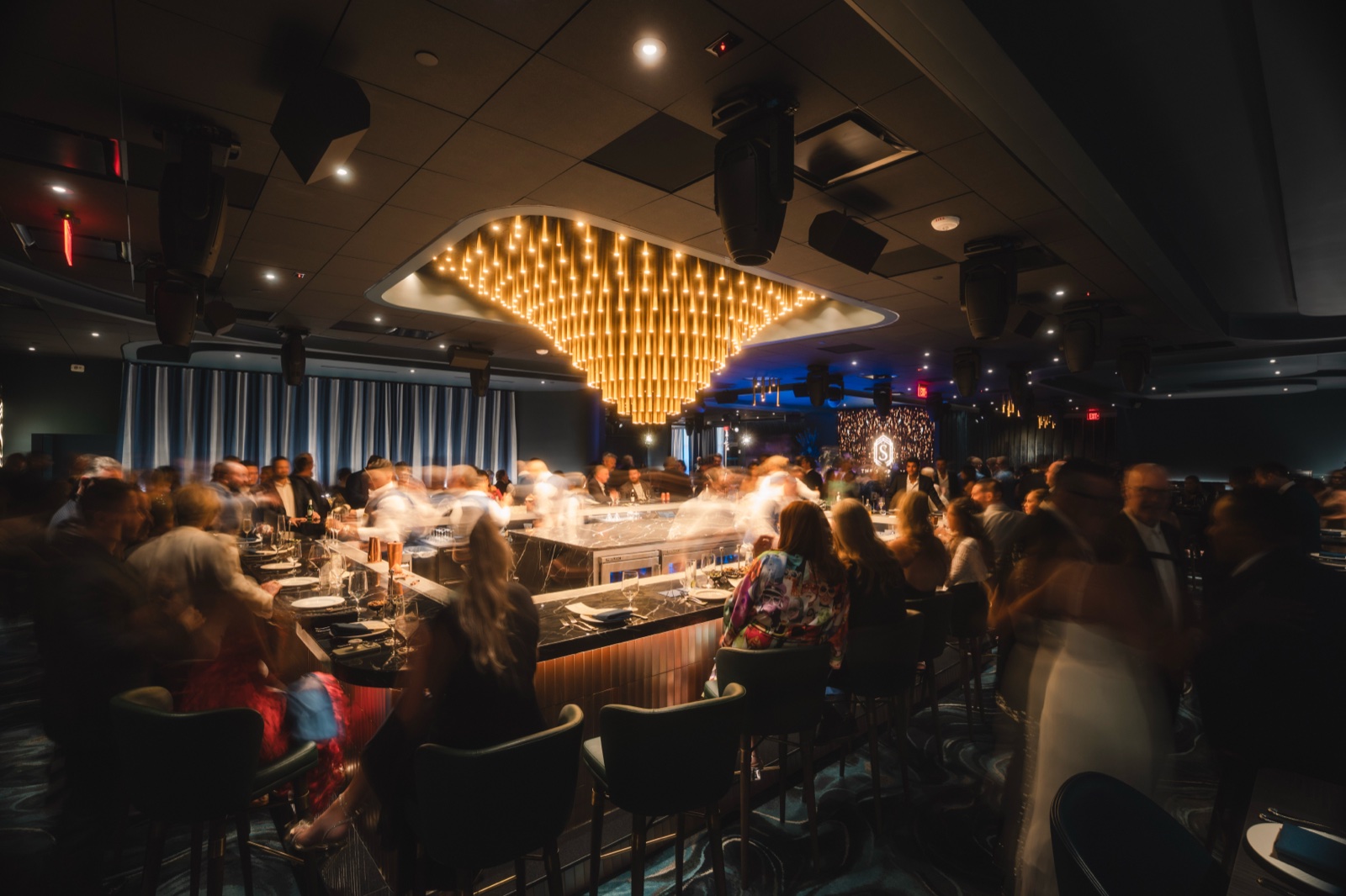 Packed bar lounge in motion beneath the chandelier