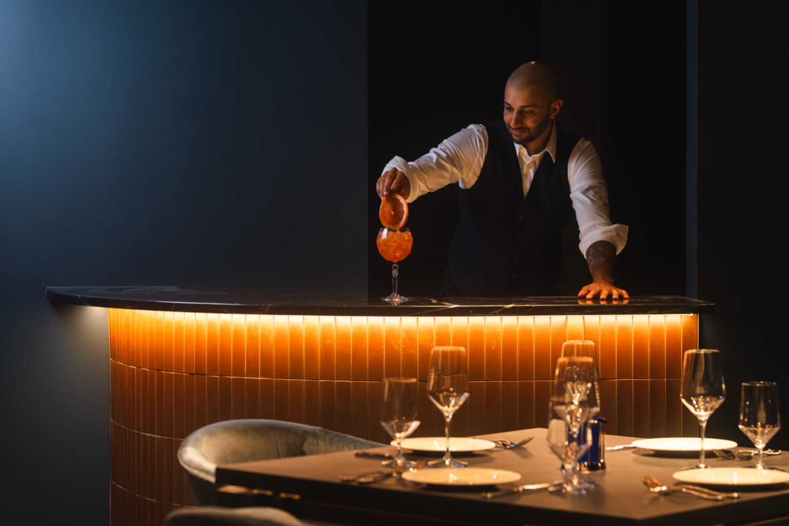 Bartender pouring a spritz over a glowing bar