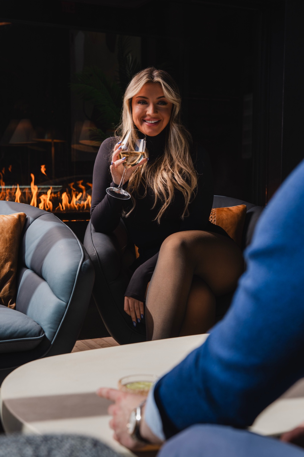 A guest with a glass of wine by the fireplace