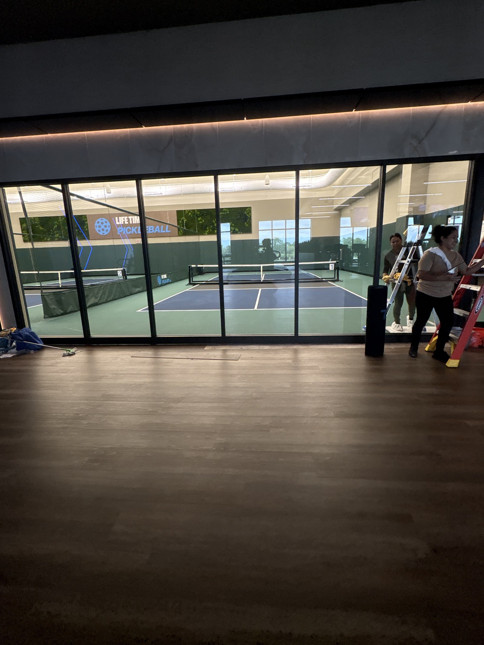 Glass doors opening onto the indoor pickleball courts.