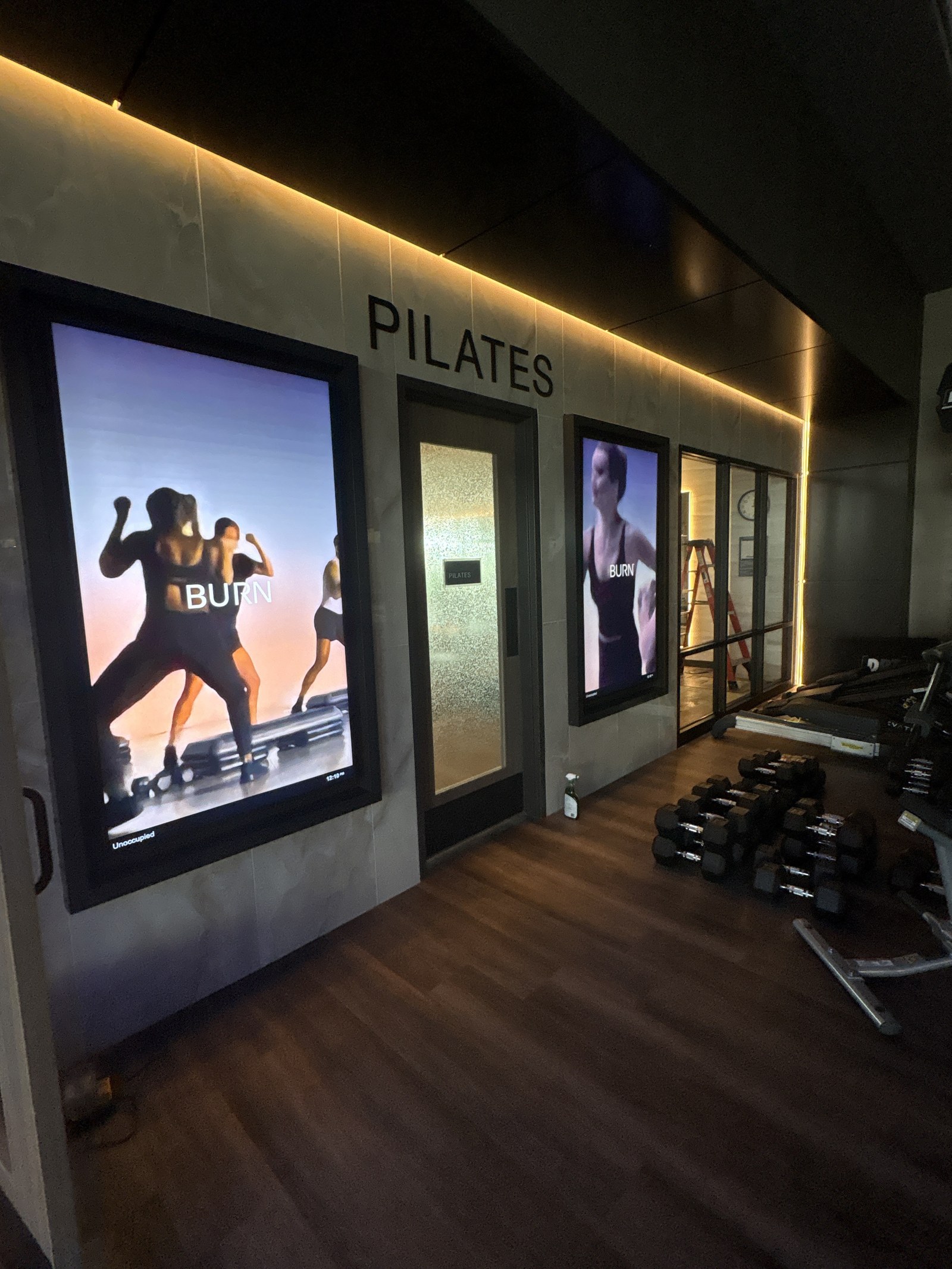 A doorway marked Pilates, flanked by lit class posters.