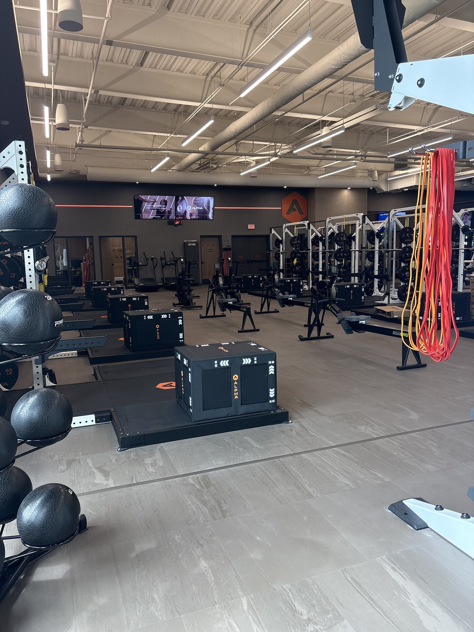 A rack of medicine balls, plyo boxes and resistance bands in the Alpha training area.