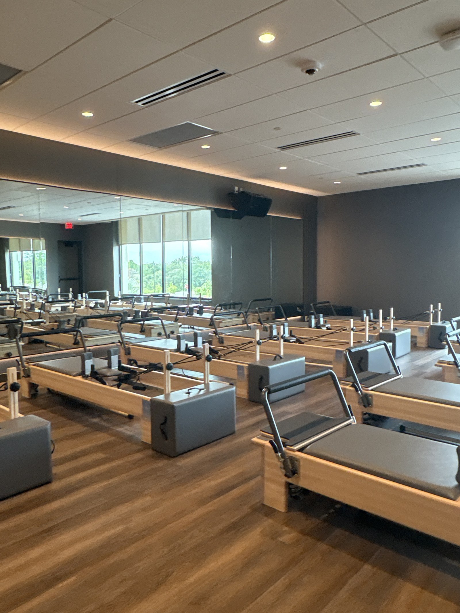 Rows of reformer machines in a studio with mirrors and windows.
