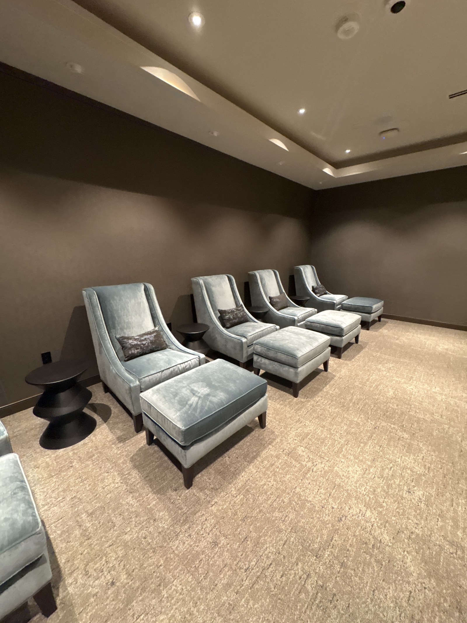 Upholstered lounge chairs and ottomans in a dim spa lounge.