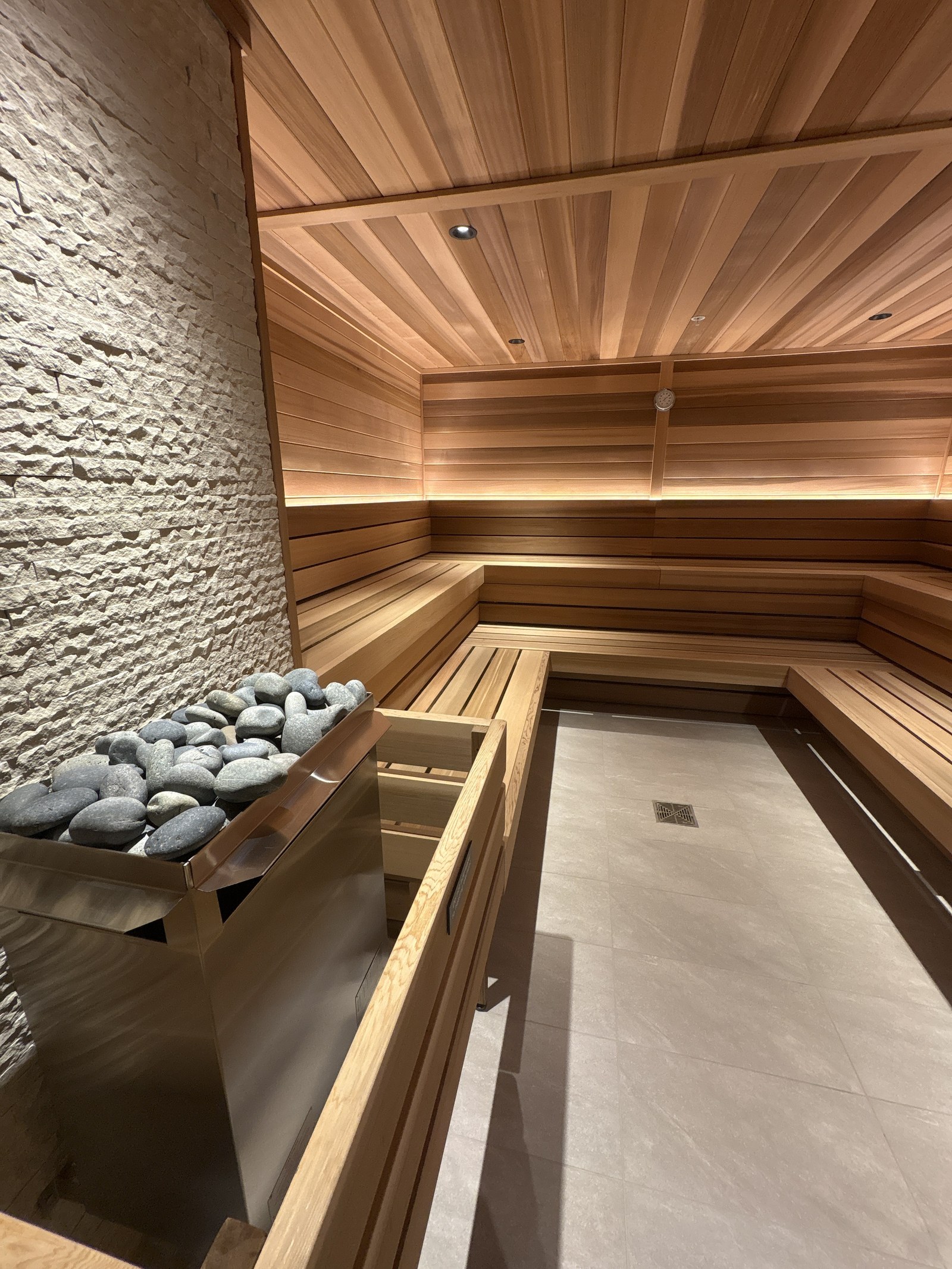 A cedar sauna with a stone heater and tiered benches.