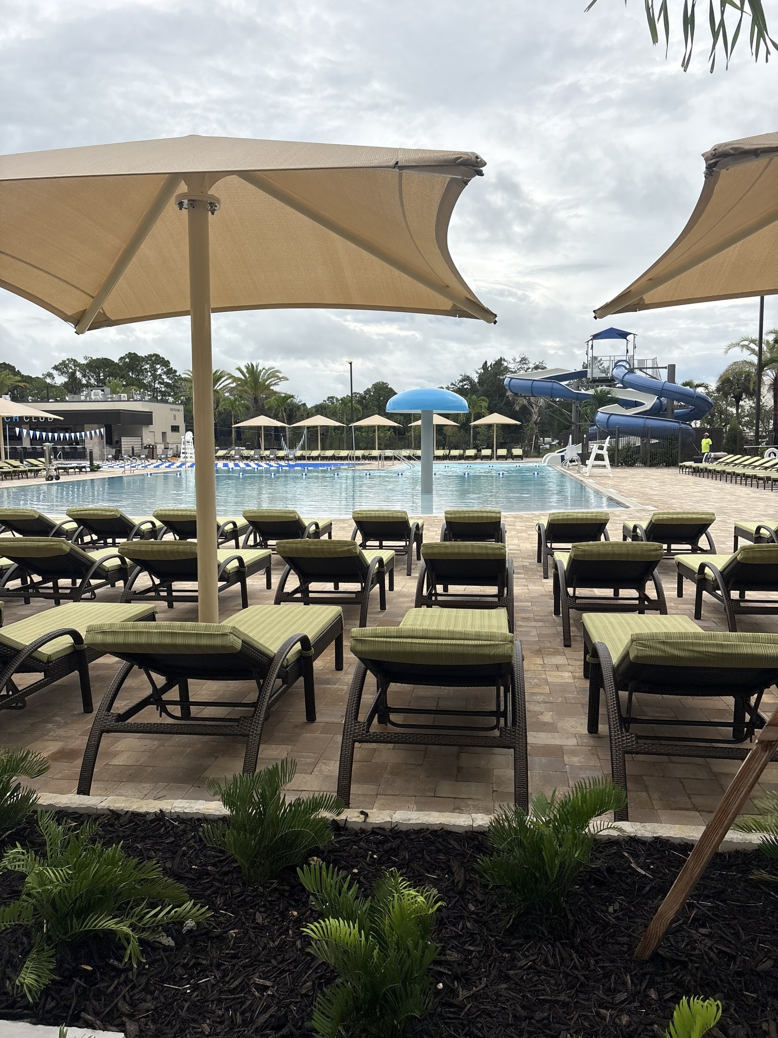 Rows of lounge chairs under shade umbrellas facing the leisure pool and waterslides.