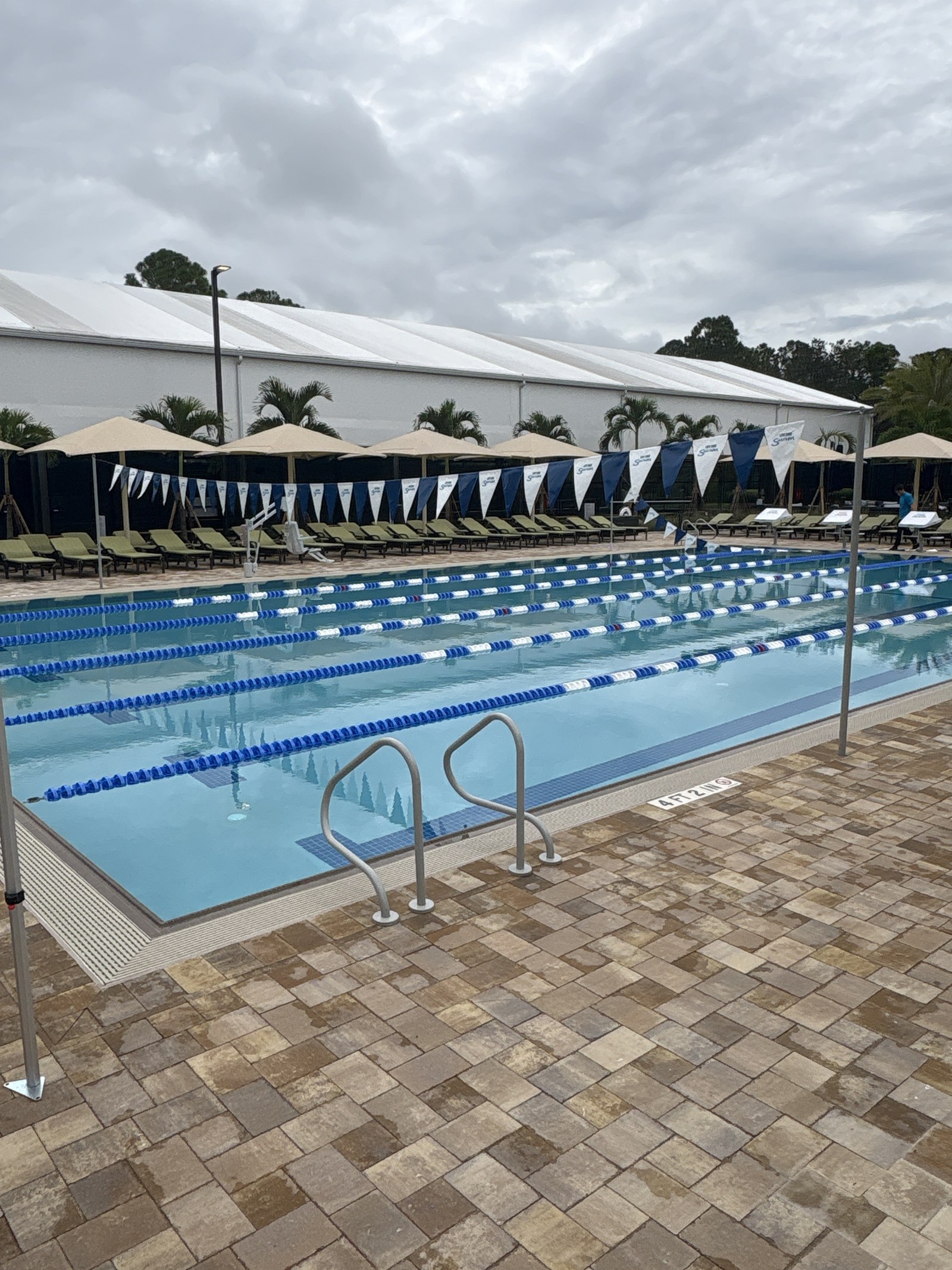 A five-lane outdoor lap pool with lane lines and a paver deck.