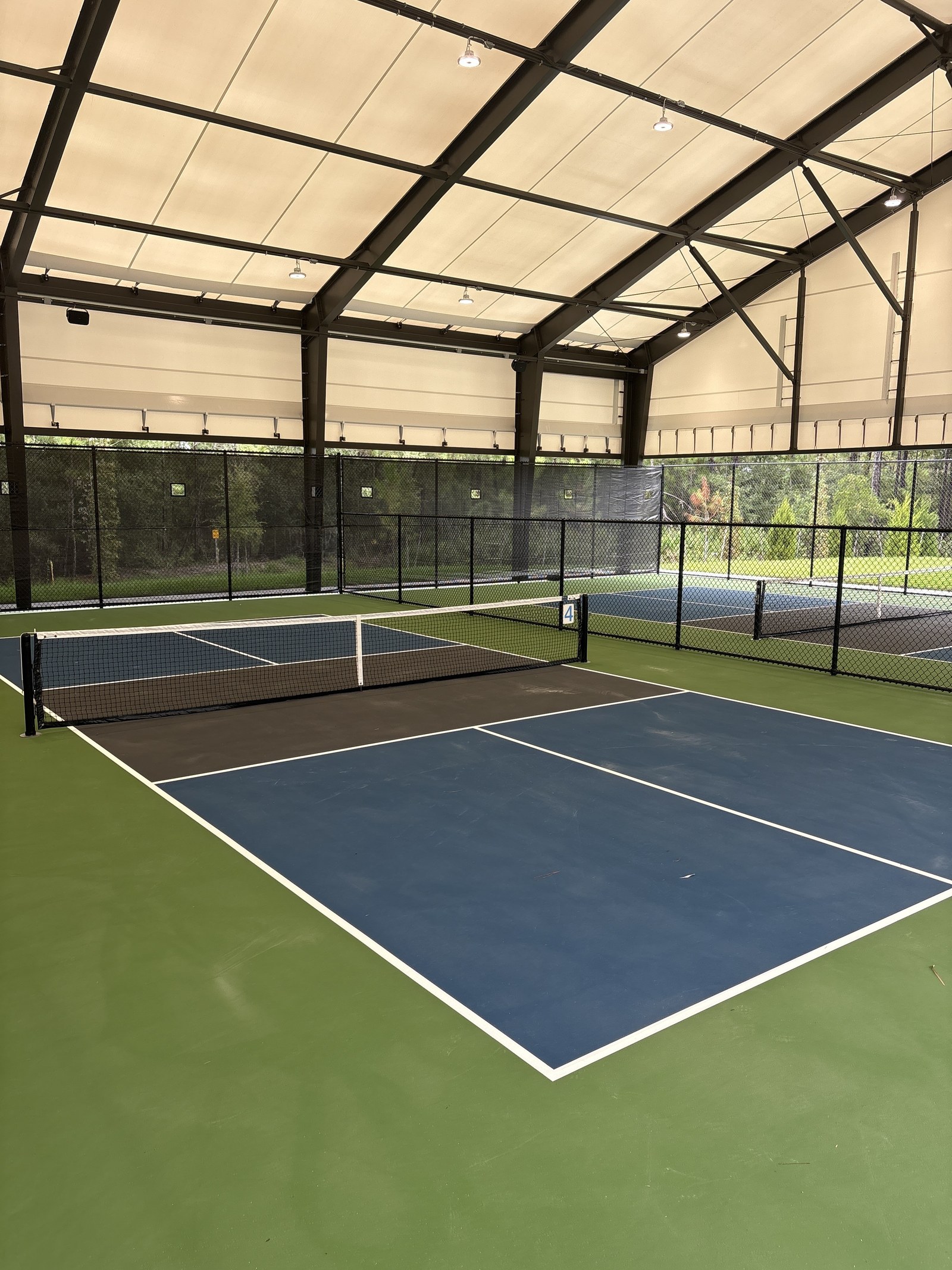 Pickleball courts under a covered steel pavilion.