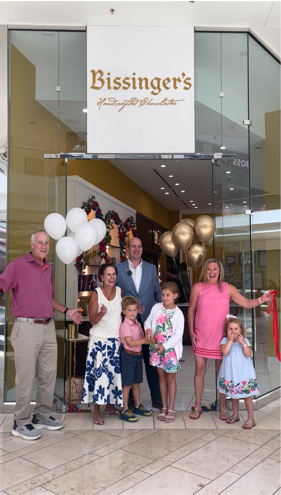 Family members and guests gathered with balloons outside the Bissinger's storefront for the ribbon cutting.